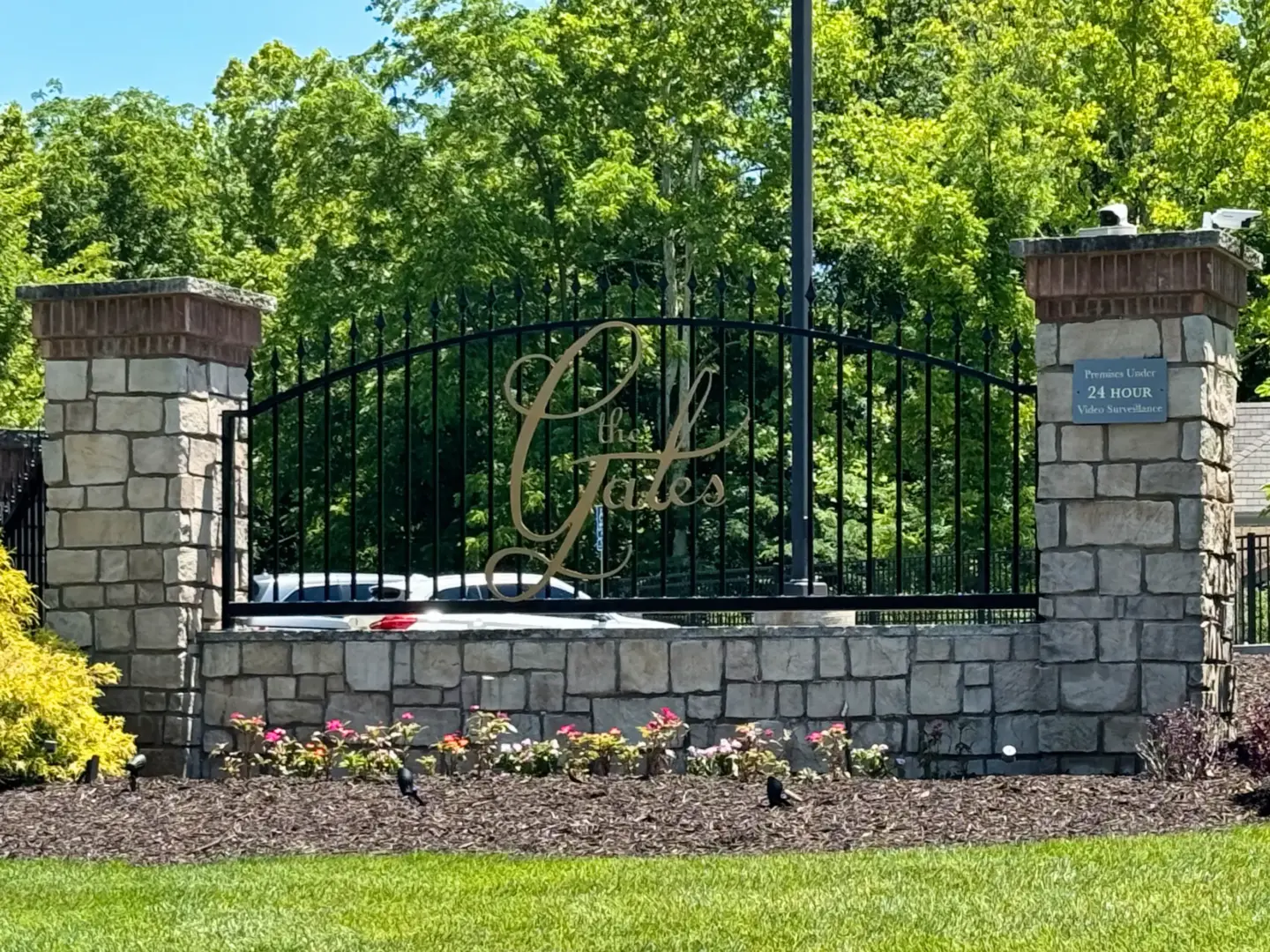 Image of the "The Gates" branding on a rock wall with steel fencing