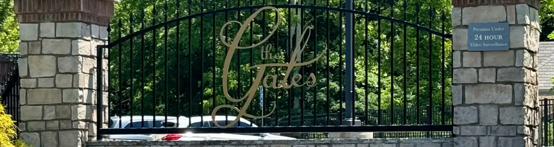 Image of the "The Gates" branding on a rock wall with steel fencing